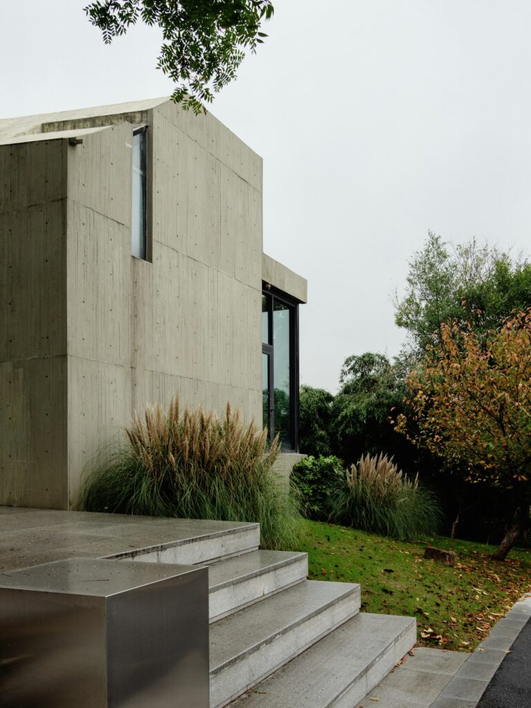 Vivienda de hormigón con grandes ventanales y vegetación